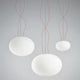 Panzeri Gilbert Glas Pendelleuchte in modernem Design, mit drei hängenden, weißen Glaskugeln und roten Kabeln.