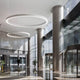 Panzeri Golden Ring LED-Pendelleuchte Dimmbar in modernem Atrium mit eleganten Säulen und viel Licht.