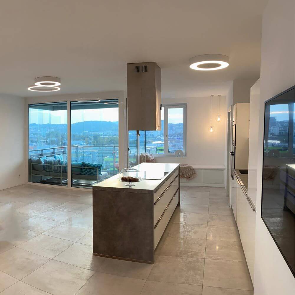 Moderne Küche mit Panzeri Silver Ring LED-Deckenlampe Dimmbar und großflächigen Fenstern.