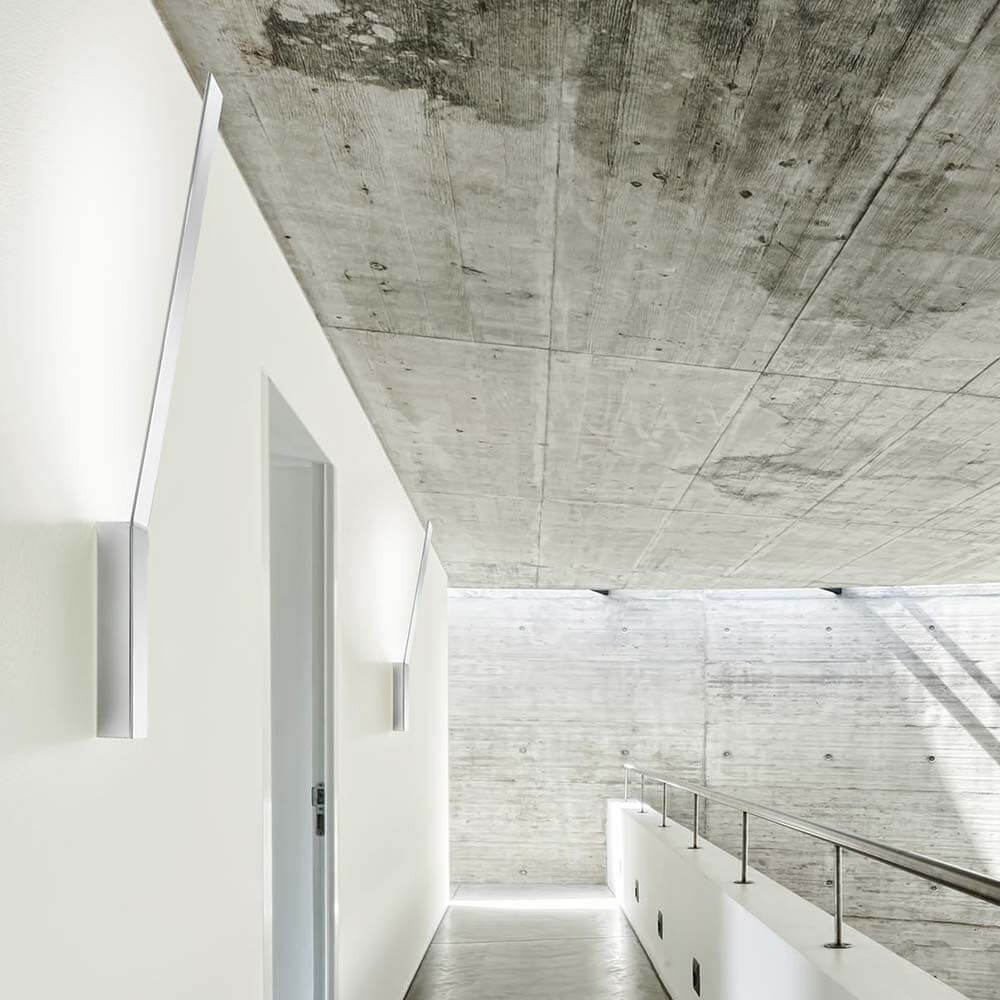 Panzeri Ypsilon LED Wandlampe indirekt in modernem Flur mit Betonwand und minimalistischer Architektur.