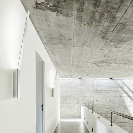 Panzeri Ypsilon LED indirect wall light in a modern hallway with concrete wall and minimalist architecture.