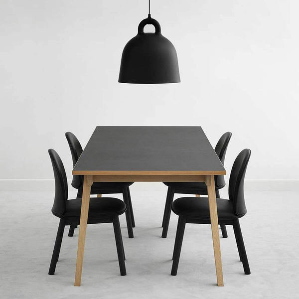 Luminária pendente Bell L Ø 55cm Preta sobre uma mesa de jantar moderna com cadeiras pretas.