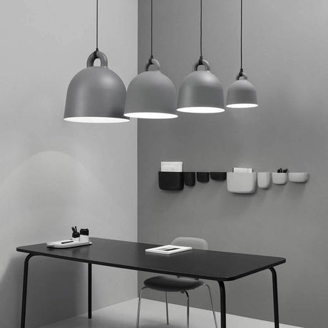Lampa wisząca Bell S Ø 35cm Szara w nowoczesnym otoczeniu z szarymi ścianami i czarnym stołem.