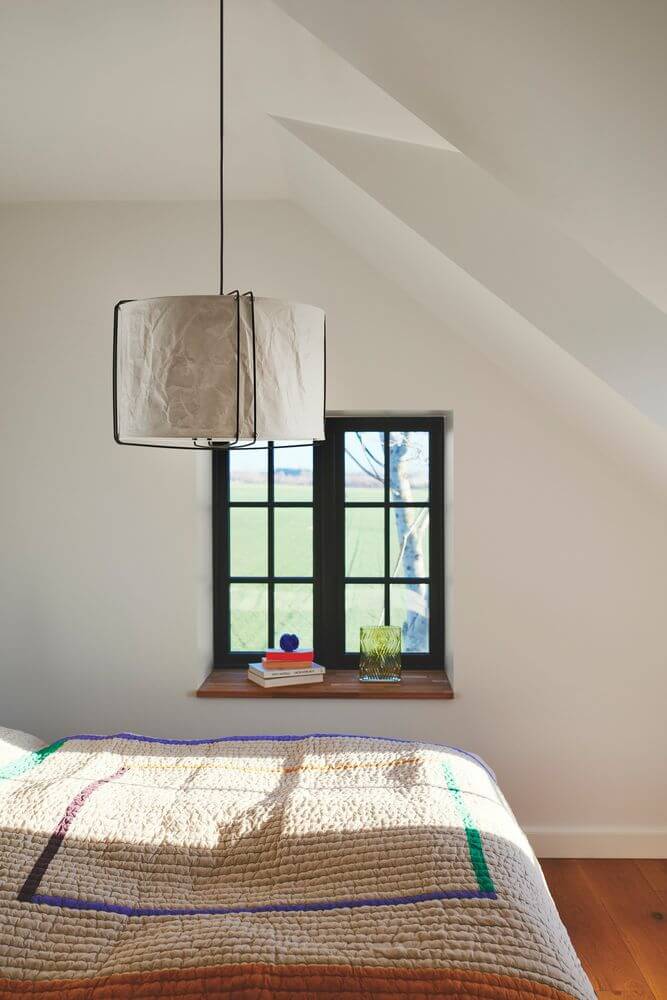 Pendelleuchte Cardine 50 im modernen Japandi-Stil über einem Bett in einem gemütlichen Schlafzimmer.