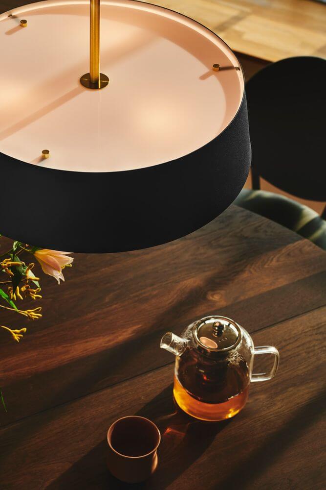 Pendelleuchte Clasi 45 über einem Holztisch mit Teekanne und Tasse, modernes Design und warmes Licht.