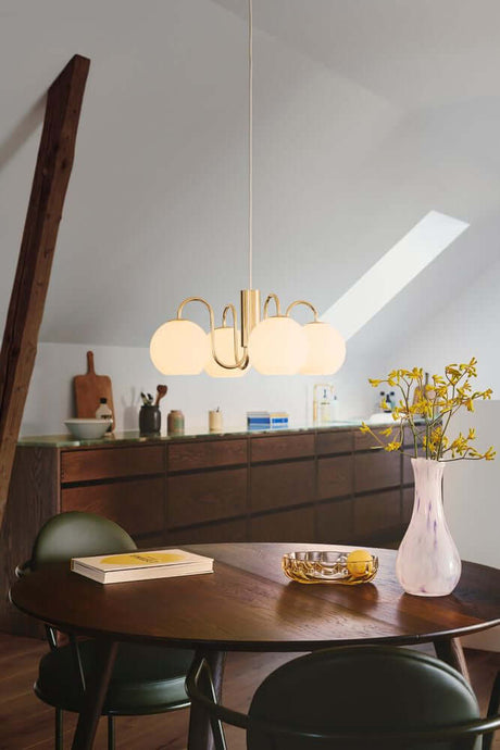 Franca pendant light above a modern dining table with elegant chairs and vases in a stylish room.