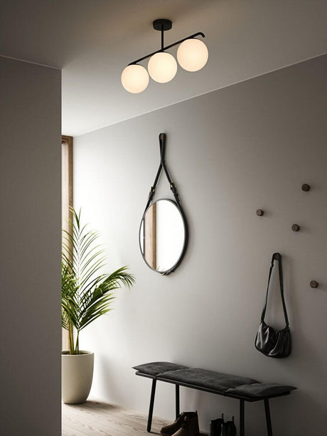 Pendelleuchte Grant 3x15 in modernem Raum mit Spiegel und Pflanze.