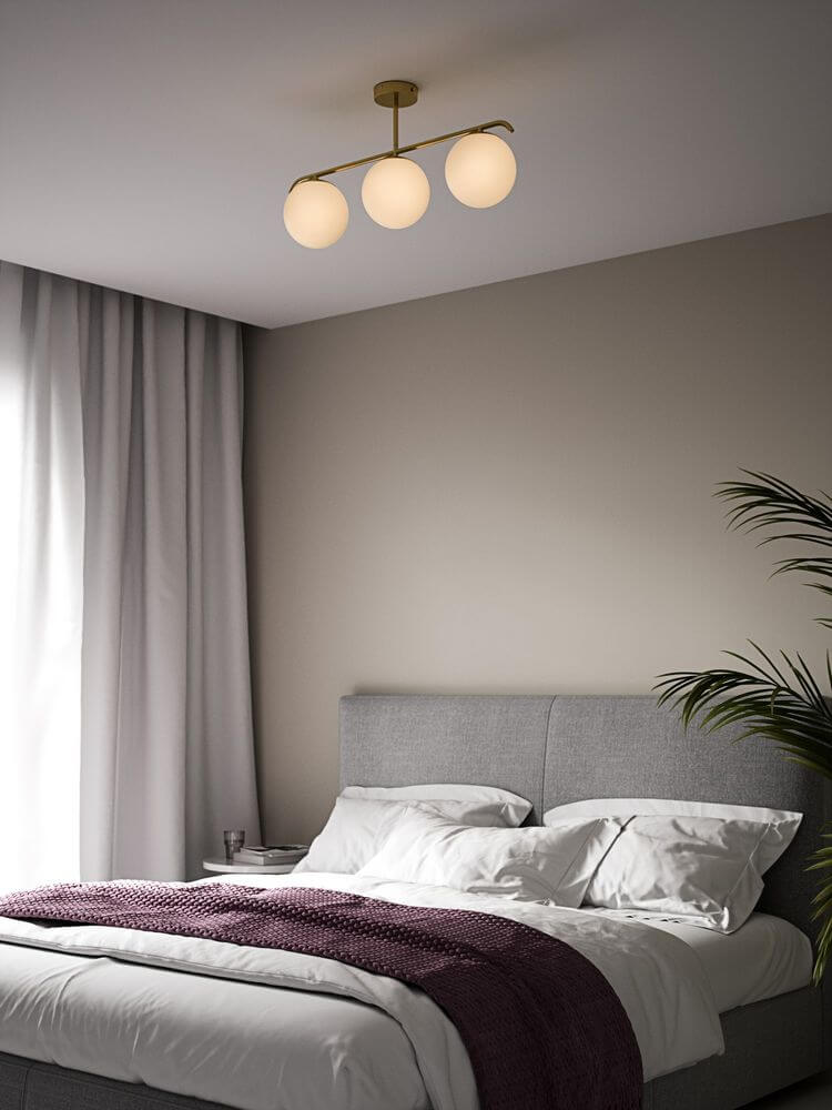 Pendelleuchte Grant 3x15 über einem modernen Schlafzimmer mit eleganter Einrichtung und sanften Farben.