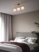 Pendelleuchte Grant 3x15 über einem modernen Schlafzimmer mit eleganter Einrichtung und sanften Farben.