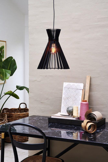 Pendelleuchte Groa 34 in modernem Design über einem Tisch mit verschiedenen Dekorationsartikeln.