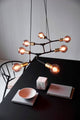Pendelleuchte Josefine 7-Spot in modernem Design über Tisch mit minimalistischen Dekorationen