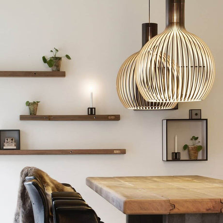 Octo Small 4241 pendant light made of wood Ø 45 cm above a wooden dining table with stylish wall shelves.