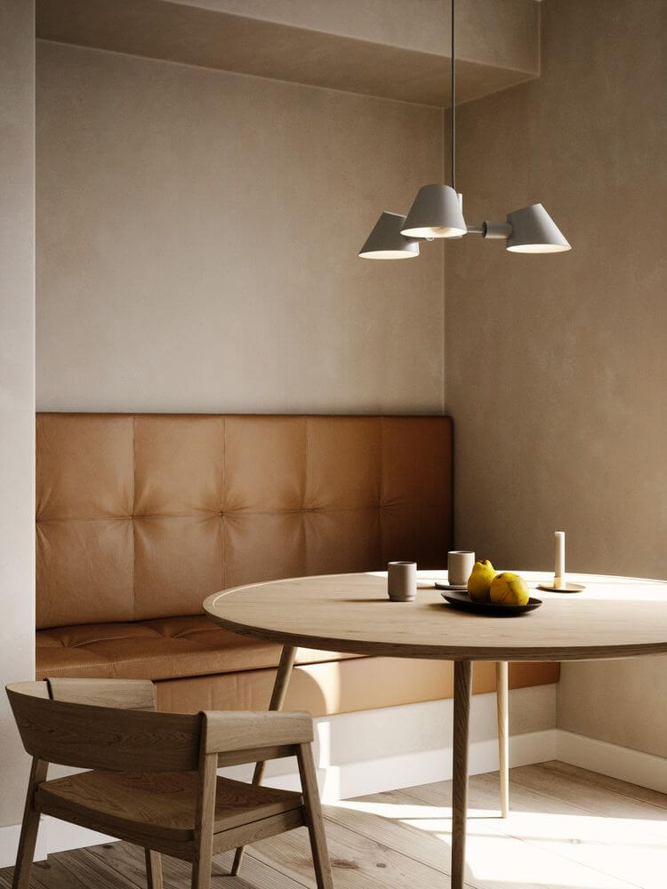 Pendelleuchte Stay 3-Spot über einem modernen Essplatz mit Holzstuhl und runder Tischanordnung.