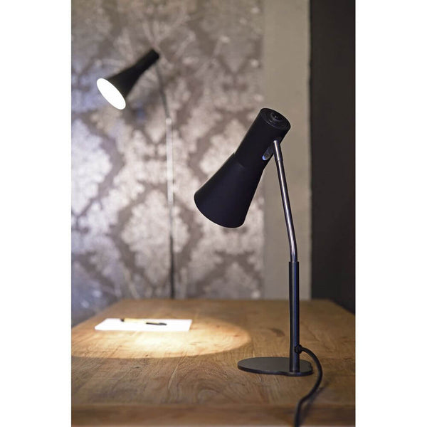 Phelia floor lamp black on a table with elegant design and conical lampshade.
