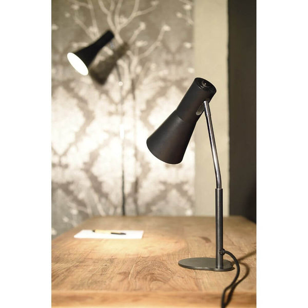 Phelia floor lamp black on a wooden desk with an elegant conical lampshade.
