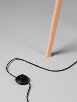 Detailaufnahme der Plette Stehlampe Natur mit Holzbein und schwarzem Kabel.