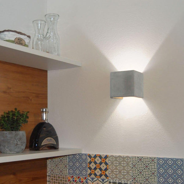 s.luce Applique Plinth in cemento grigio su una parete, illuminazione indiretta moderna e design elegante.