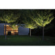 Plug & Shine LED Boden Einbauleuchte Grau IP67 beleuchtet Bäume in einem Garten.