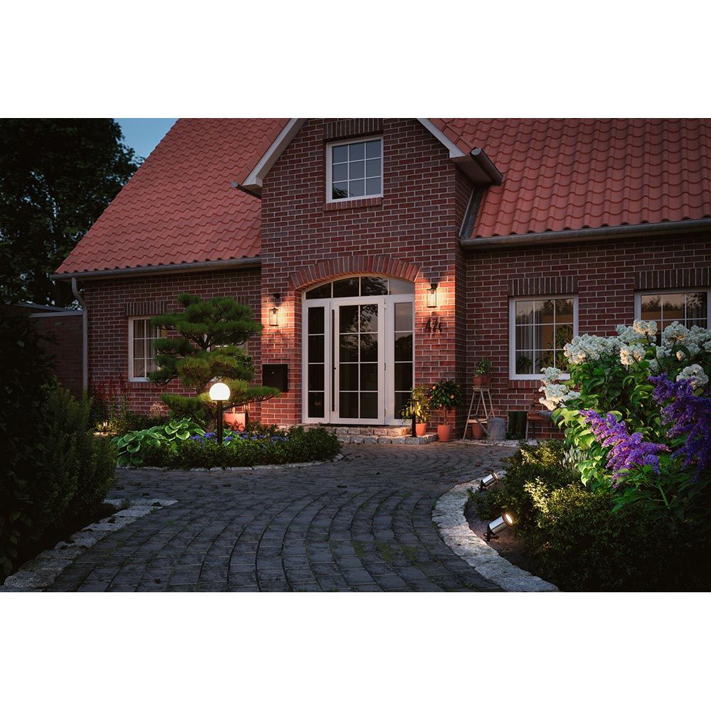 Eingang eines Hauses mit Pollerleuchten und Gartenbeleuchtung für eine einladende Atmosphäre bei Nacht.