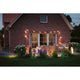 Gemütlicher Gartenbereich mit Plug & Shine LED Spieß-Pollerleuchte Classic Mini Anthrazit vor einem Backsteinhaus.