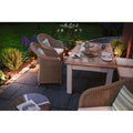 Gemütliche Terrasse mit rattan Stühlen, Holztisch und stimmungsvoller Beleuchtung im Freien.