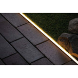 Plug & Shine Neon-Stripe Profil 1m installierter LED Strip auf gepflastertem Boden und Rasen.