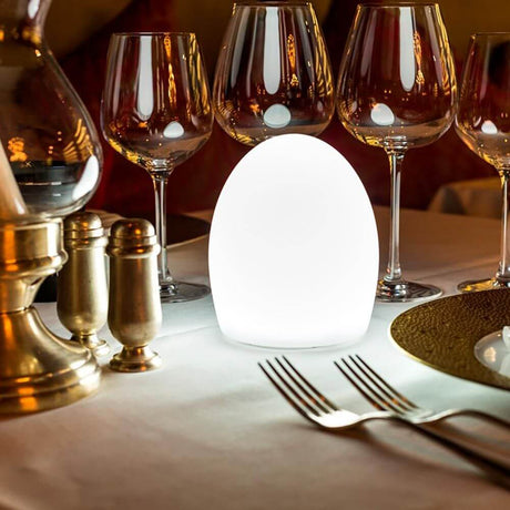 Candeeiro de mesa Point Aida Akku LED com controlo por aplicação sobre uma mesa elegante num restaurante.