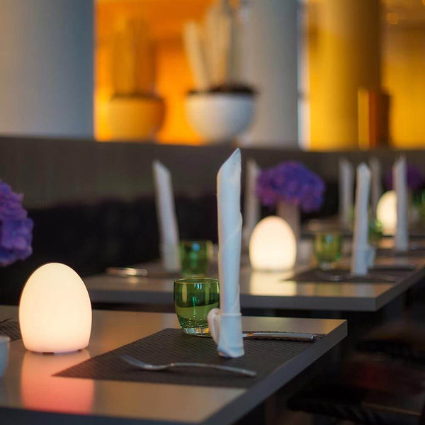 Point Aida Akku LED table lamp with app control on an elegantly set table in a restaurant.