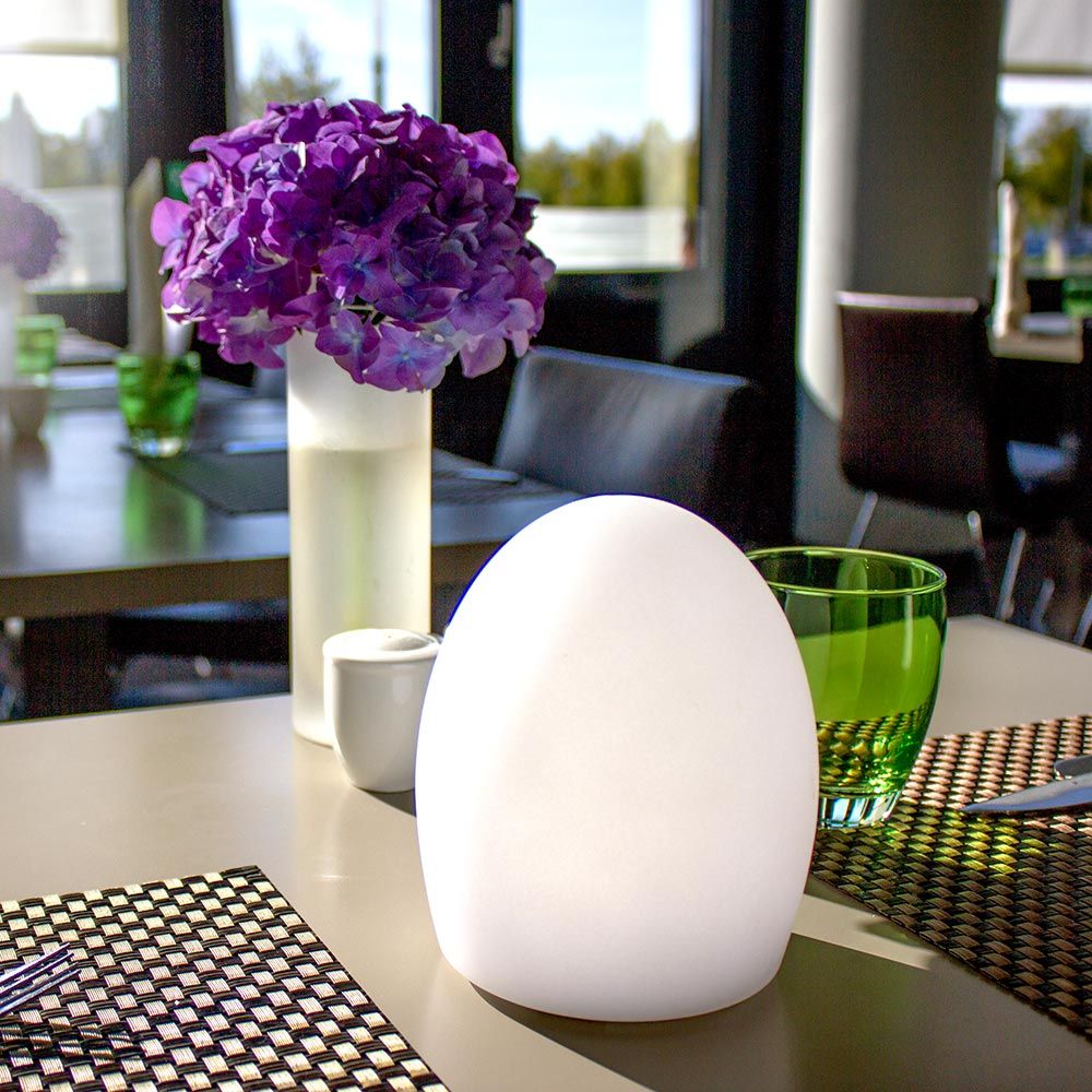 Akku LED-Tischlampe Point Aida auf einem eleganten Tisch mit Blumen und Gläsern im Hintergrund.