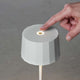 Hand betätigt die dimmbare LED-Akkuleuchte Positano in modernem Design für den Außenbereich.