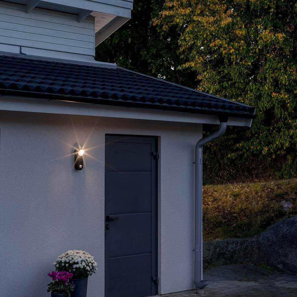 Prato Batterie LED Außen-Wandlampe mit Bewegungsmelder Schwarz an einer Wand bei Nacht.