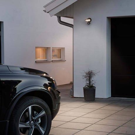 Prato LED projecteur extérieur avec détecteur de mouvement noir à côté de la porte d’entrée d’une maison au crépuscule.