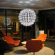 Superstar Design-Kronleuchter 100cm in modernem Raum mit orangefarbenen Stühlen und elegantem Design.