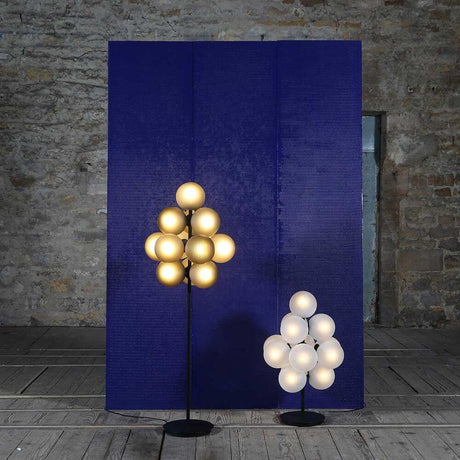Pulpo LED vloerlamp Stellar Grape Big 13-lichts naast kleinere lamp voor blauwe muur in moderne ruimte.