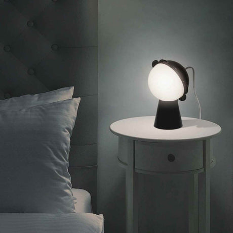 Daisy table lamp on a bedside table next to a bed, radiant light in the bedroom.