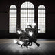Fallen Chandelier M Akku Bodenleuchte im Innenraum mit großen Fenstern und futuristischem Design.