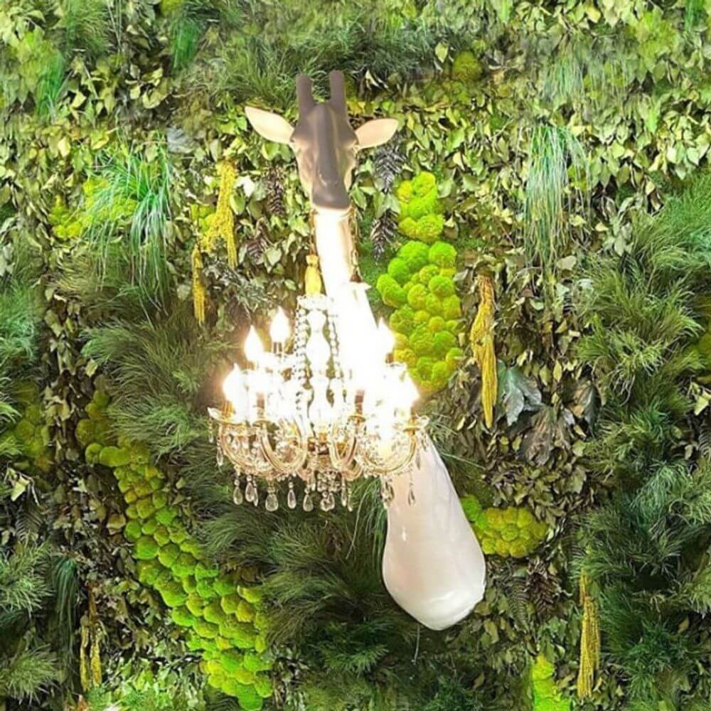 Giraffe in Love Wandleuchte 173cm mit klassischem Kronleuchter in grünem Naturhintergrund.
