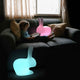 Ein Kind sitzt auf einem Sofa mit der Rabbit LED Dekolampe, die in bunten Farben leuchtet.