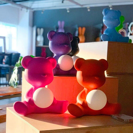 Teddy Girl rechargeable table lamp in colorful shades on a shelf, designed by Stefano Giovannoni.