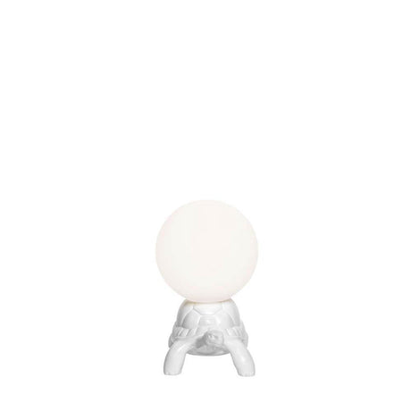 Turtle Carry XS LED rechargeable table lamp with a white turtle shell and glowing sphere in a bright room.