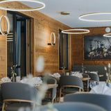 Moderne s.luce Ring Hängeleuchten in einem stilvollen Restaurant mit Holzdekor.