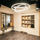 Moderne s.luce Ring Hängeleuchte im minimalistischen Raum mit Holzregal und Sitzgelegenheit.