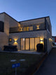 Rold LED Außen-Wandleuchte IP44 Schwarz beleuchtet moderne Fassade und Eingang in der Dämmerung.