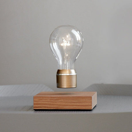 LED-decorative table lamp floating light bulb with transparent glass body and oak wood base.
