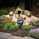 Gartensteckdose IP44 im Garten mit Töpfen und Pflanzen, 1,4m Zuleitung sichtbar, ideal für Außenanschlüsse.
