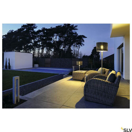 Lampadaire d’extérieur Adegan Manila IP44 en rotin sur une terrasse moderne la nuit avec mobilier en rotin.