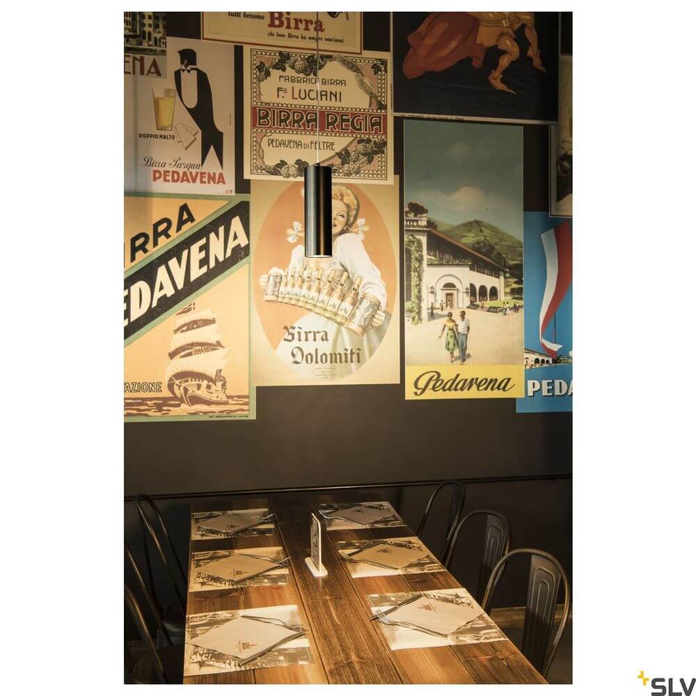 Anela Reflektor 28° Schwarz über einem Tisch mit italienischen Bierplakaten im Hintergrund.