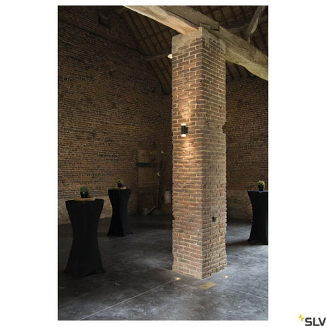 Astina wall light QPAR51 Up & Down Black on a brick pillar in a stylish interior.