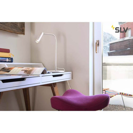 Lampe de table Karpo LED blanche 3000K sur un bureau avec chaise violette et vue sur la terrasse