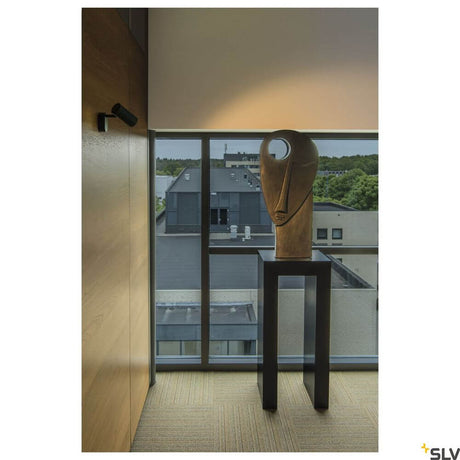 Noblo I spotlight 2700K black illuminates a modern art sculpture in an elegant room.